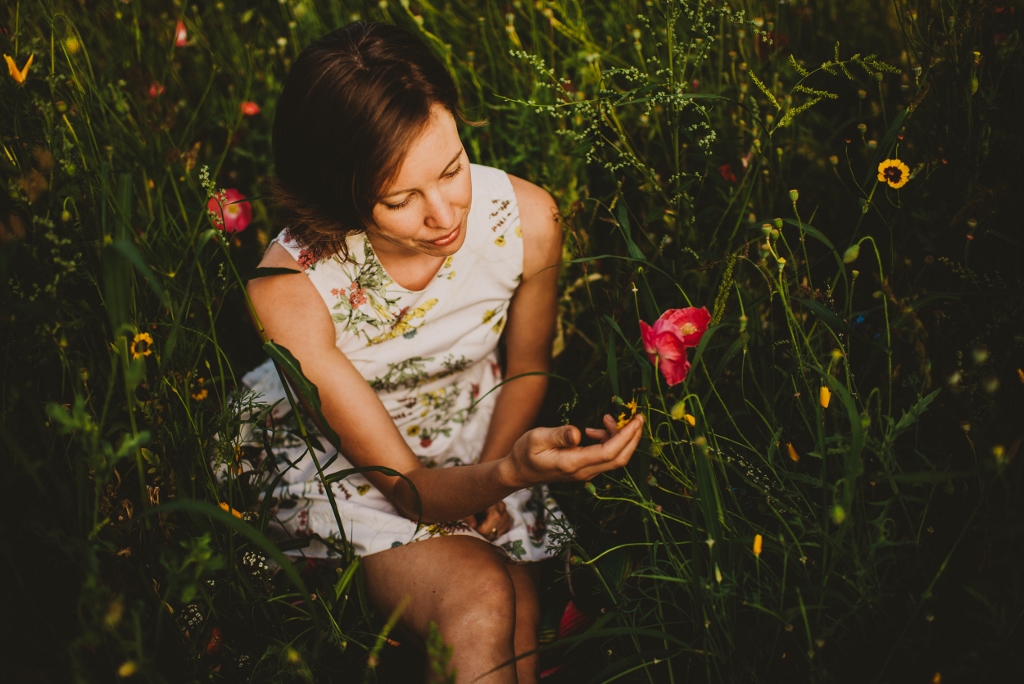 Lisa Matthews in a flower field with her hand on a flower